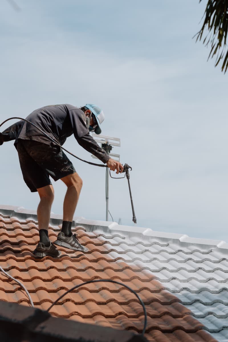 Professional roofer spray painting roof coating